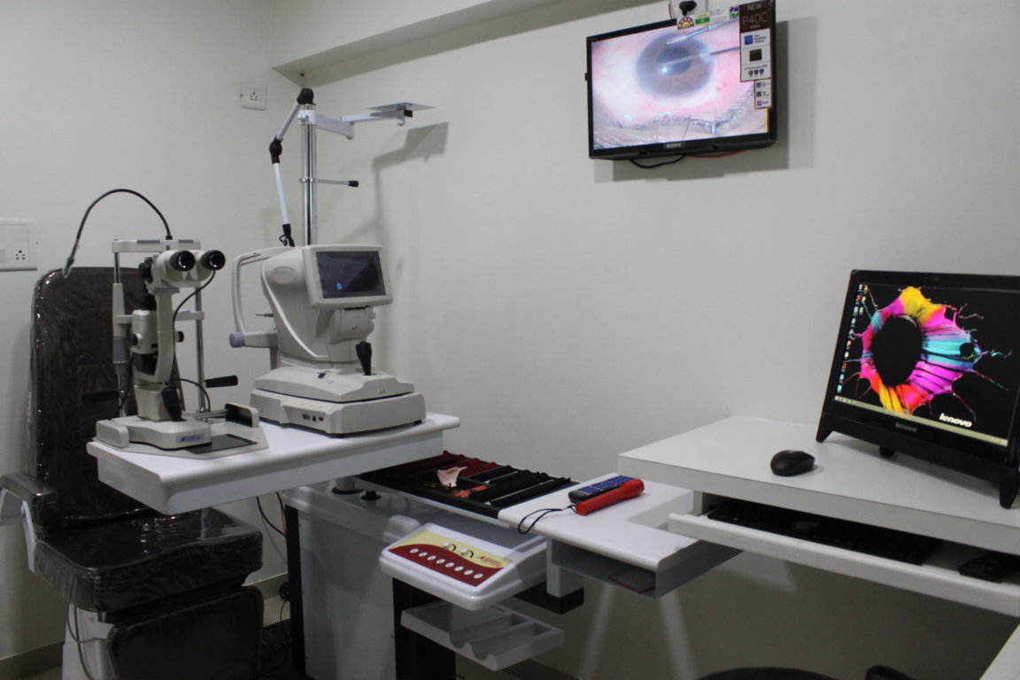 Combined autorefraction and slit-lamp diagnostic bay at Insight Institute with a topography monitor, patient chair and ophthalmic surgery video display